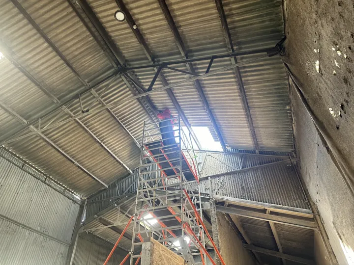 A D&M commercial roof removal job with a worker on a scaffold tower
