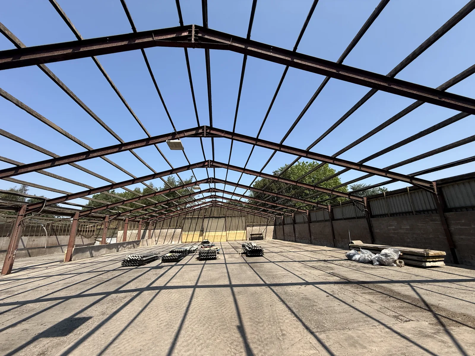 Barn roof structure exposed after the roof sheets were removed, with removed material still on the floor awaiting final clearance