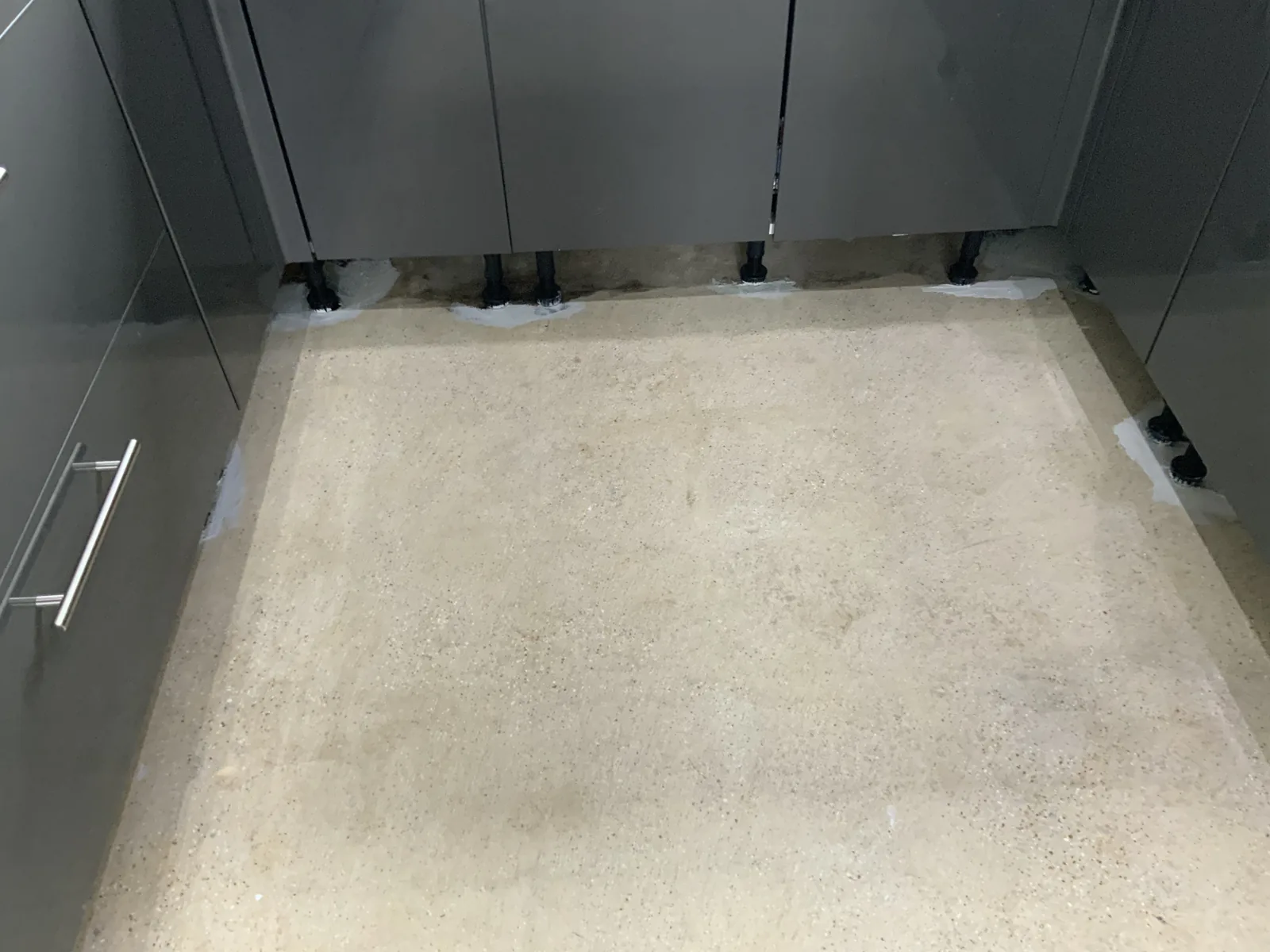 Concrete floor exposed after tile and bitumen removal; inaccessible bitumen remnants encapsulated with ET150