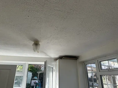Textured ceiling above a rear door and windows before removal
